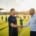A Local Business Owner Is Shaking Hands With A Youth Sports Coach At A Community Field, Symbolizing Partnership And Community Involvement. This Interaction Highlights The Importance Of Local Sponsorships And Support For Local Youth Sports Teams, Fostering Connections Within The Local Community.