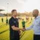 A Local Business Owner Is Shaking Hands With A Youth Sports Coach At A Community Field, Symbolizing Partnership And Community Involvement. This Interaction Highlights The Importance Of Local Sponsorships And Support For Local Youth Sports Teams, Fostering Connections Within The Local Community.
